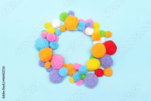 Circle of colorfull fluffy balls on blue background. Pile of colorfull fluffy balls. Fluffy textile balls circle frame on blue background.