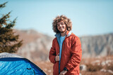An afro man in the early morning in front of a mountain tent prepares a travel backpack
