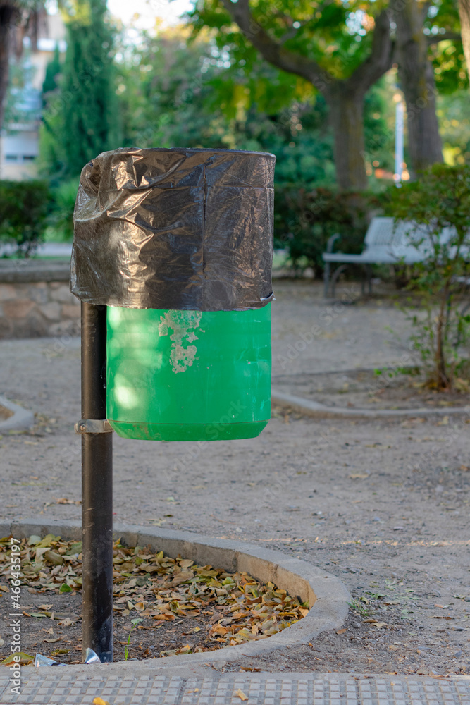 papelera de color verde con bolsa de basura de color negro para tirar basura en un jardín publico papelera de color verde con bolsa de basura de color negro para tirar basura en un jardín publico