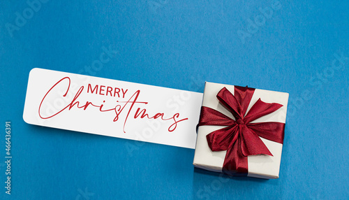 Close up gif box on blue background and white card with merry christmas