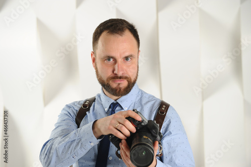 A man of European appearance with a beard with a camera. Business dress, shirt, tie, jacket. Commercial photographer for a business meeting, conference, reportage.