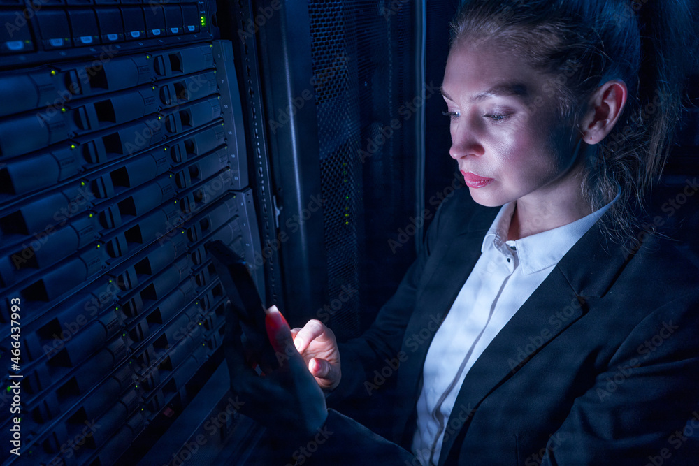 Fototapeta premium Woman engineer working in datacenter by server storage racks