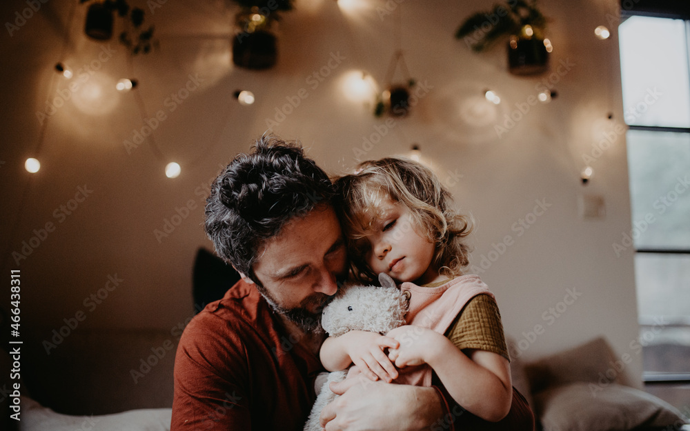 Mature father with sad small daughter hugging indoors at home. Mature father with sad small daughter hugging indoors at home.