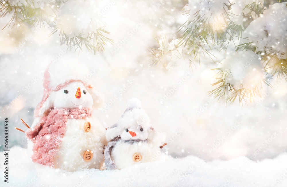 Christmas snow composition with two cute snowmen in hats and scarves in snowdrift and fir branches on gray background