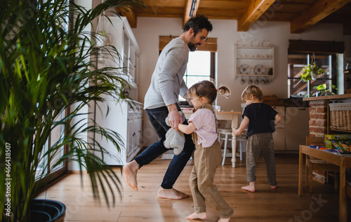 Obraz na plátně Mature father with two small children dancing indoors at home.
