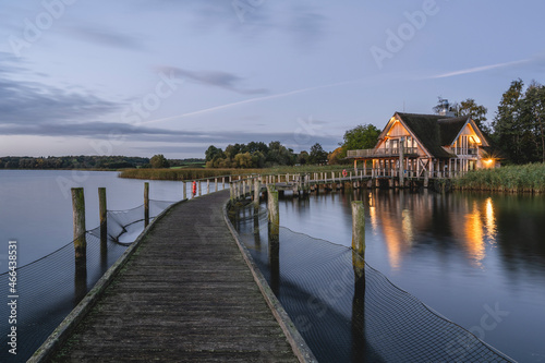 Germany, Schleswig-Holstein, Hemmelsdorf, Vogelplattform Hemmelsdorfer See observation deck at dusk with lakeshore house in background photo