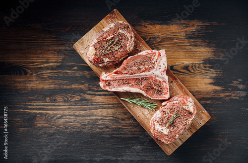 Obraz na płótnie three lovely raw marbled black Angus beef steaks flavored with a mixture of ground pepper and ready to cook and serve on a dark wooden background. w salonie