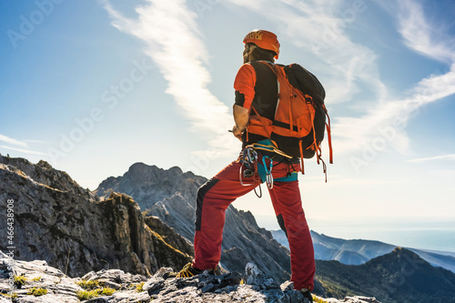 Male alpinist with backpack standing on mountain photo