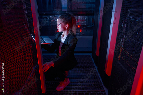 System administrator with laptop examining in server room