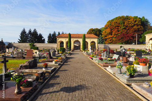 Italian cemetery entrance gate with main alley way diminishing perspective, autumn sunshine.