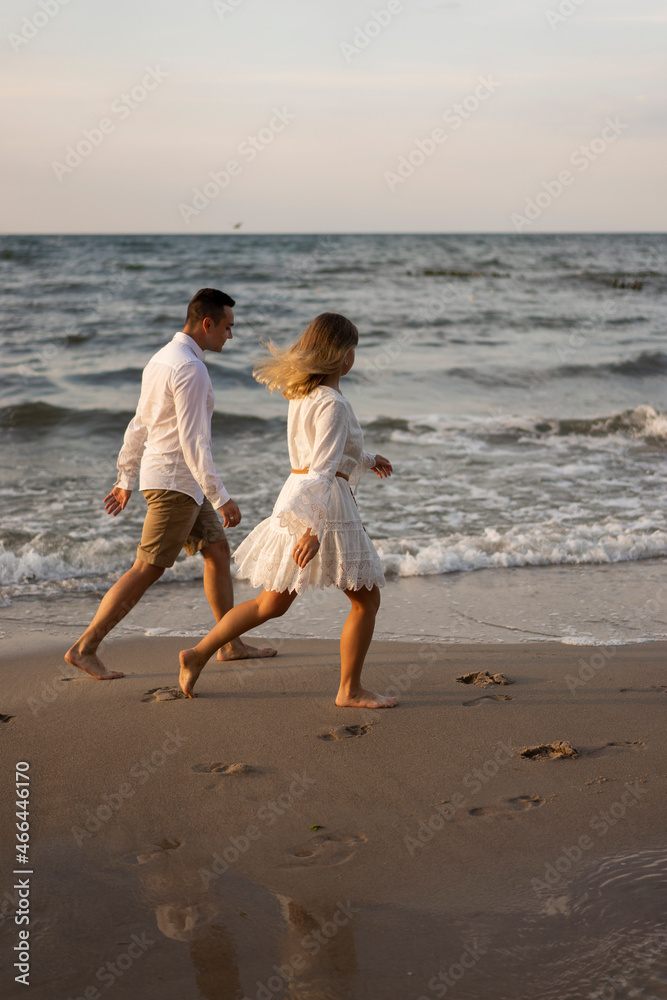 Couple running by sea at beach on sunset Couple running by sea at beach on sunset