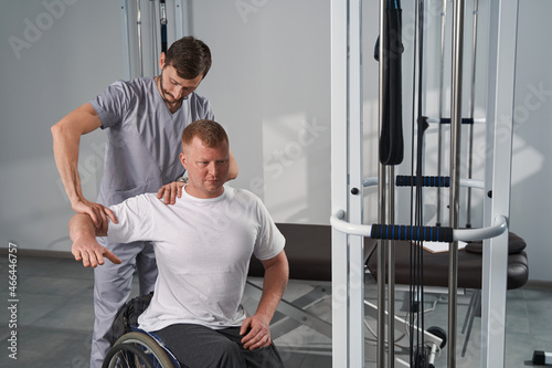 Manual therapist treats man with disability shoulder joint flexibility