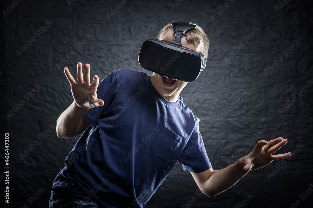 Boy using a virtual reality headset reacting and jumping to something scary he's seen Boy using a virtual reality headset reacting and jumping to something scary he's seen