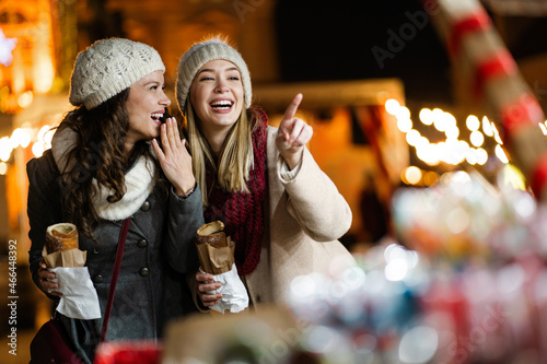 Happy women friends enjoying christmas market and having fun together outdoors. photo