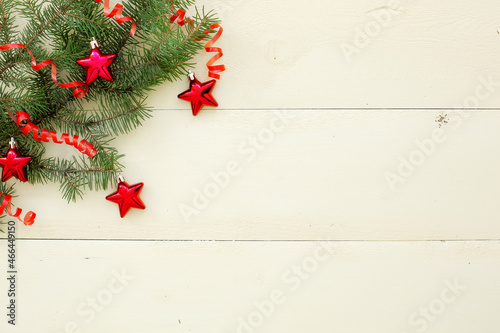 fir twigs with red balls in the form of stars on a white wooden background. New Year background, top view, whiteboards
