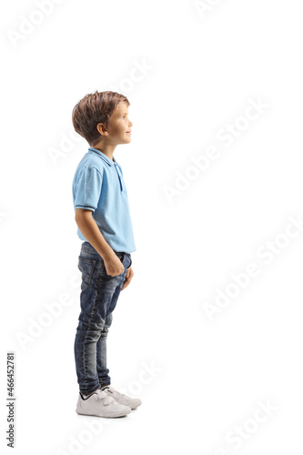 Full length profile shot of a boy in a blue t-shirt standing and watching something photo