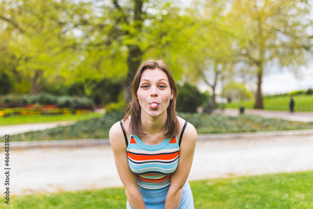 Playful woman sticking out tongue at public park Playful woman sticking out tongue at public park