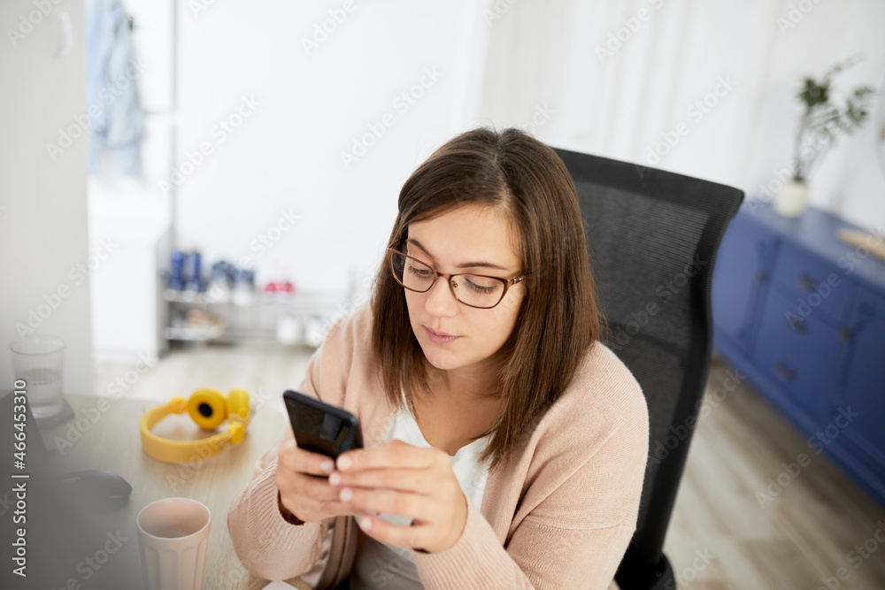 Female freelancer using smart phone while working at home Female freelancer using smart phone while working at home