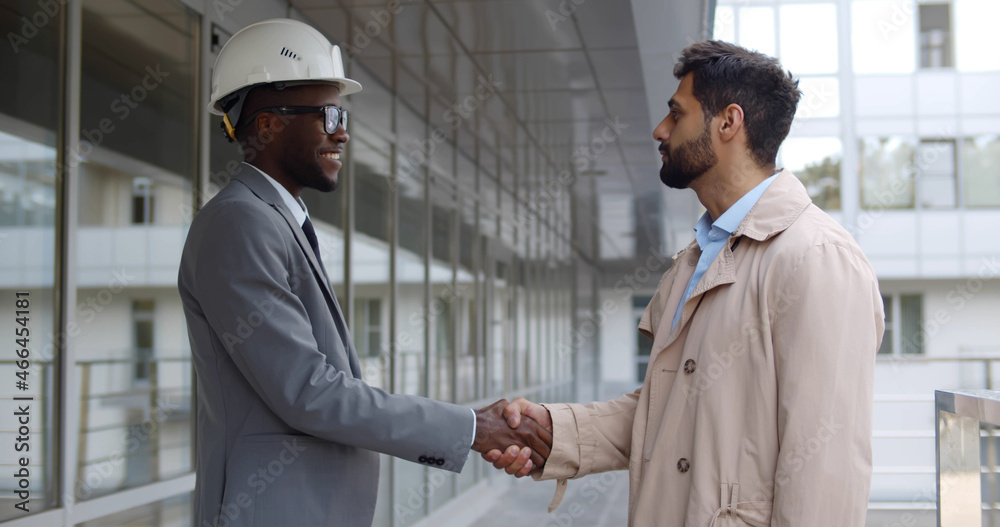 Businessman and engineer talk and shake hands outdoors