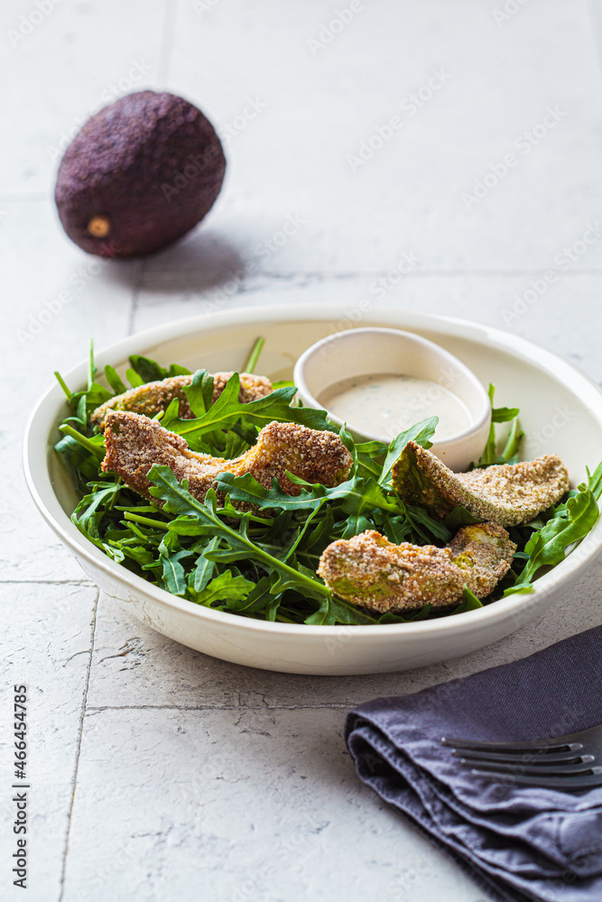 Batter-fried avocado with arugula and tahini dressing. Vegan food concept. Batter-fried avocado with arugula and tahini dressing. Vegan food concept.