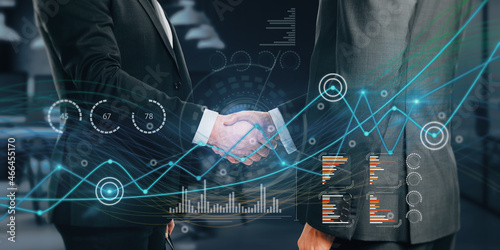 Close up of businessmen shaking hands with creative glowing business graph on blurry background. Innovation, teamwork, information and statistics concept. Double exposure.