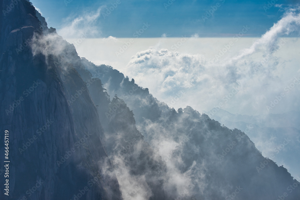 A dynamic view of white clouds surrounding a granite mountain. Landscape of Mount Huangshan (Yellow Mountain). UNESCO World Heritage Site. Anhui Province, China.