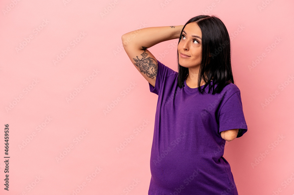 Young pregnant woman with one arm isolated on pink background touching back of head, thinking and making a choice.