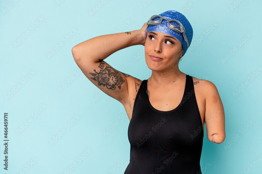 Young swimmer caucasian woman with one arm isolated on blue background touching back of head, thinking and making a choice. Young swimmer caucasian woman with one arm isolated on blue background touching back of head, thinking and making a choice.