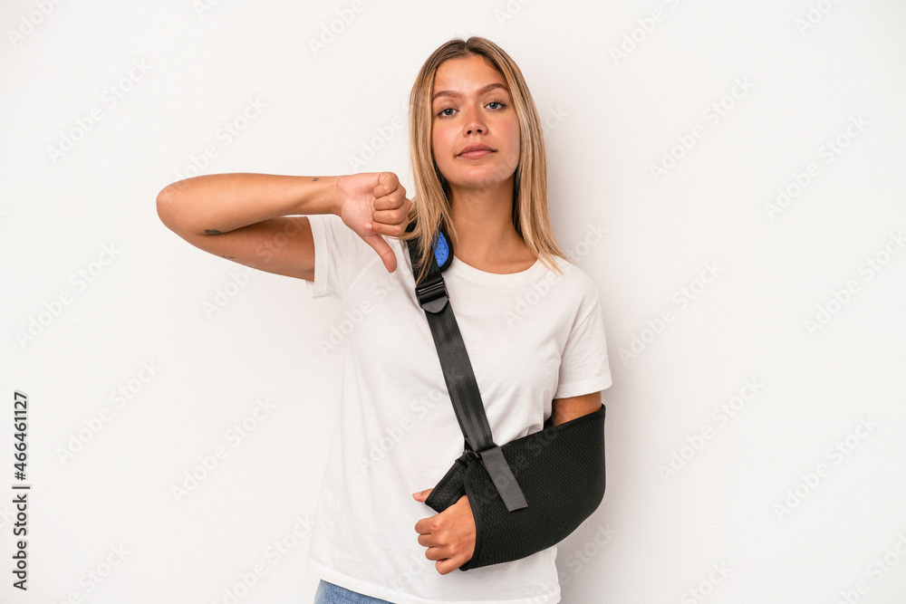 Young caucasian woman with broken hand isolated on white background showing a dislike gesture, thumbs down. Disagreement concept. Young caucasian woman with broken hand isolated on white background showing a dislike gesture, thumbs down. Disagreement concept.