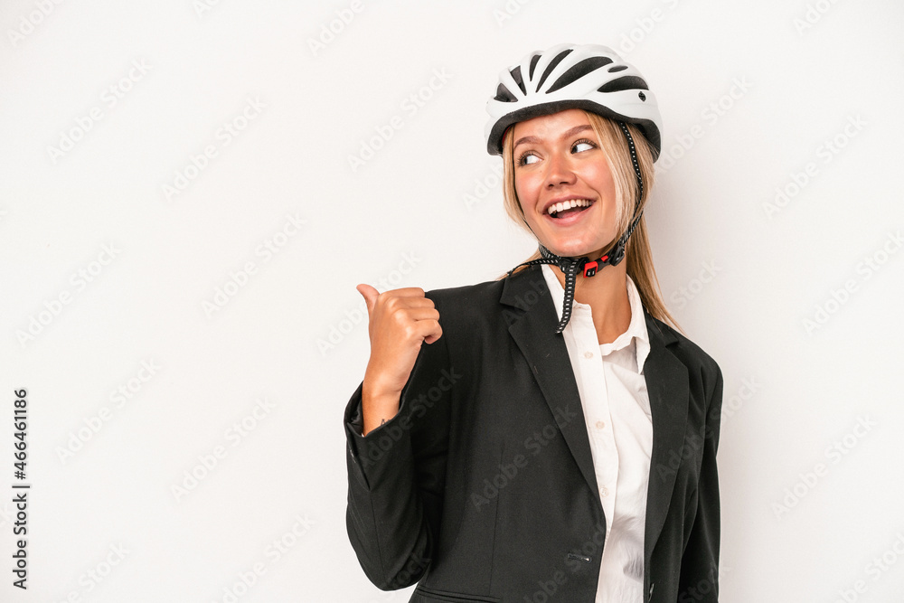 Young caucasian business woman wearing a bike helmet isolated on white background points with thumb finger away, laughing and carefree. Young caucasian business woman wearing a bike helmet isolated on white background points with thumb finger away, laughing and carefree.