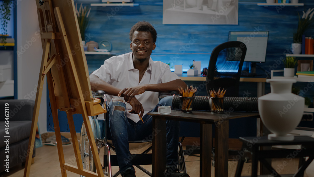 Portrait of disabled african american artist at creativity studio. Black young person with handicap sitting in wheelchair and drawing vase design on canvas for modern masterpiece project