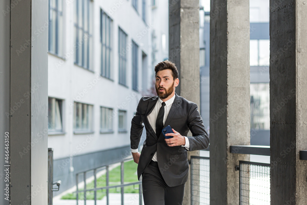 Successful businessman with a beard in a business suit runs in a hurry to a meeting near the office on the stairs Successful businessman with a beard in a business suit runs in a hurry to a meeting near the office on the stairs