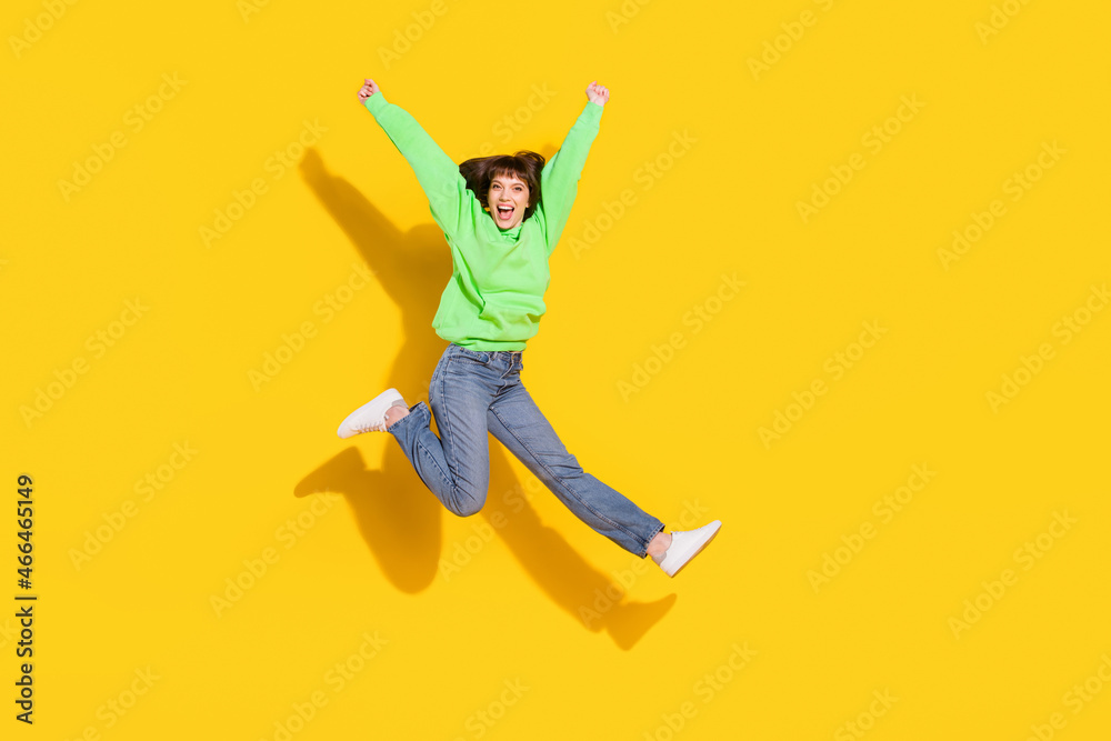 Full length body size view of pretty cheerful girl jumping rejoicing holiday isolated over bright yellow color background