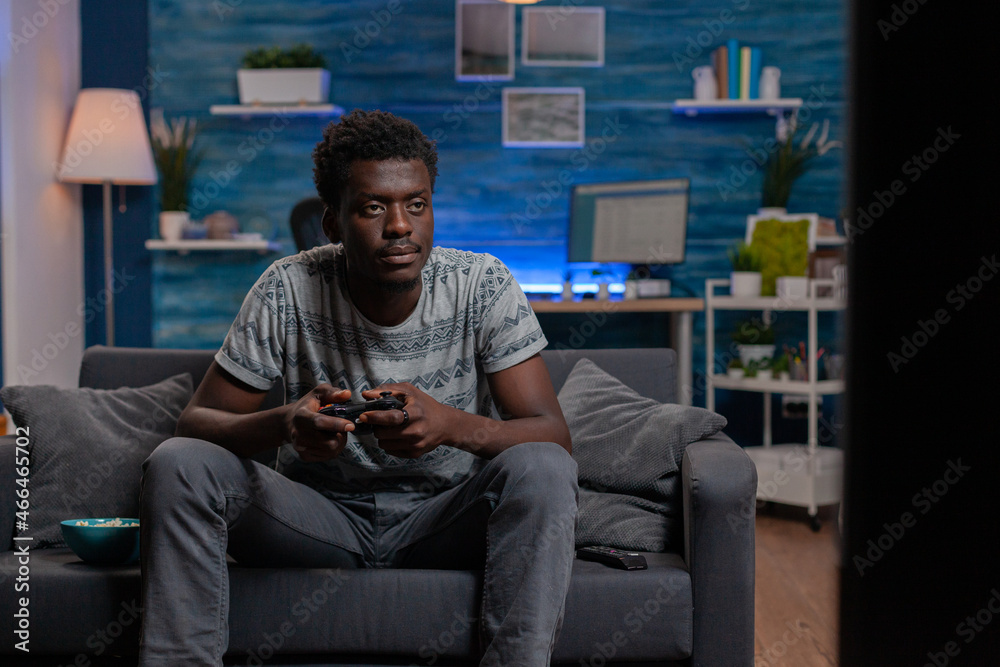 African american man using console playing virtual video games on television for free time activity.Black person playing videogames with joystick on TV for entertainment. Online competition
