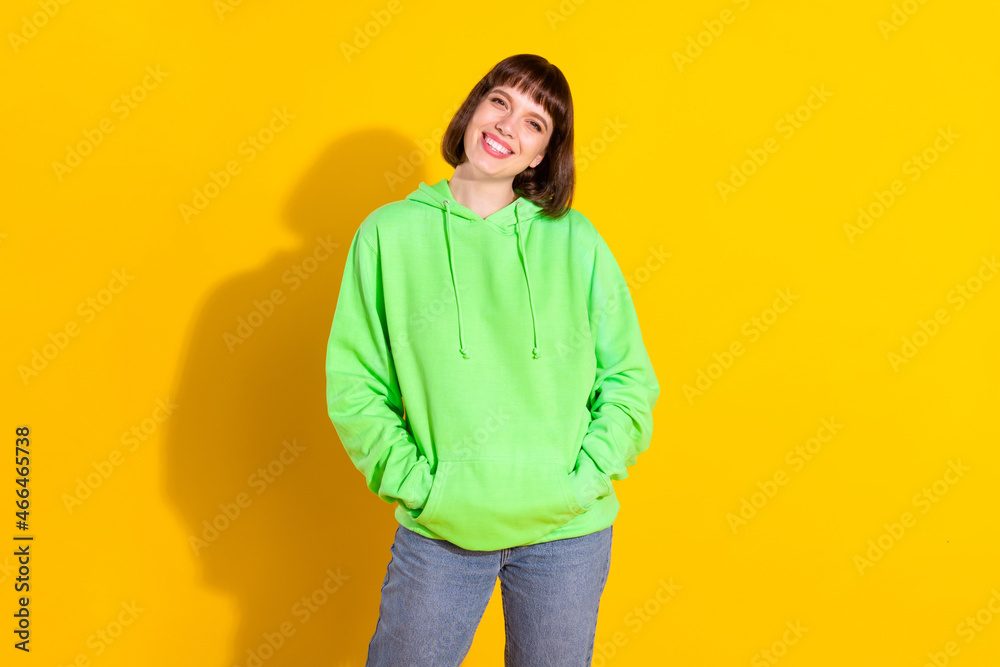 Portrait of attractive cheerful girl holding hands in pockets isolated over bright yellow color background Portrait of attractive cheerful girl holding hands in pockets isolated over bright yellow color background