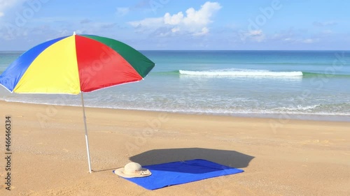 A beautiful morning Phuket beach with brightly colored umbrellas and towels laid on the beach.	
