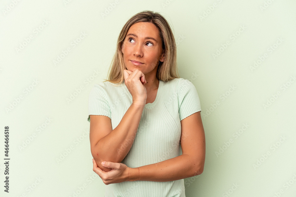 Young caucasian woman isolated on green background thinking and looking up, being reflective, contemplating, having a fantasy. Young caucasian woman isolated on green background thinking and looking up, being reflective, contemplating, having a fantasy.