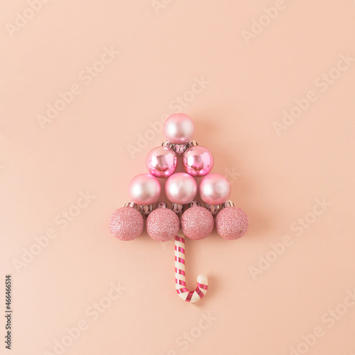 Christmas balls and lollipop making Christmas tree on pink background.