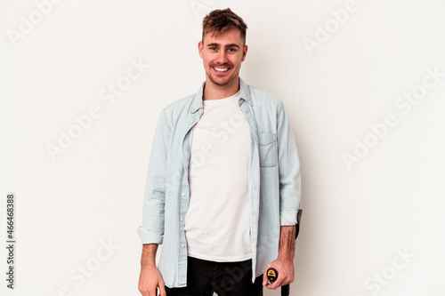 Young caucasian man holding crutch isolated on white background happy, smiling and cheerful. photo