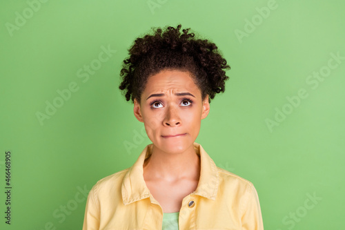 Photo of worried millennial brunette lady look up wear yellow shirt isolated on green color background
