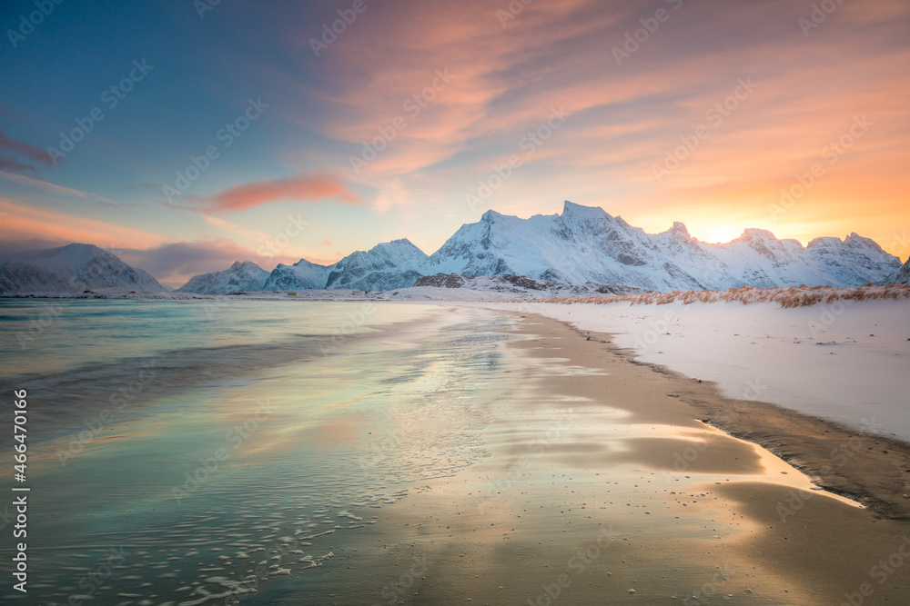 Winter morning over the sea and mountains, colorful northern sunrise and sunlight in pink clouds.