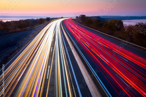 Light trails of cars on the road. Sunset time. Transport creative background. Long exposure, motion and blur.