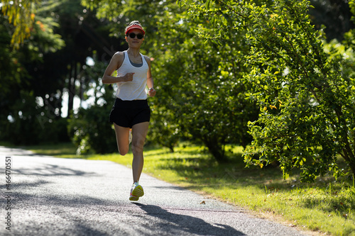 Fitness woman running on sunny tropical park trail