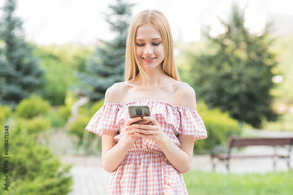 Naklejka premium Happy and attractive blonde girl holding a smartphone. Online working. Freelance