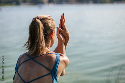 young woman in blue clothes doing yoga garudasana