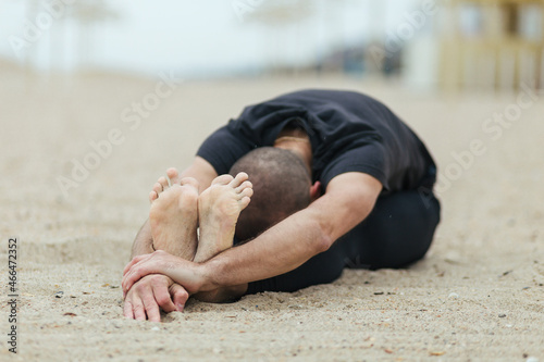 a man doing yoga stretching on the beach, balance, fitness, stretching and relaxation	