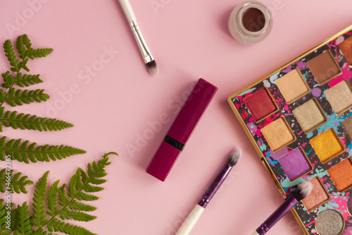 Makeup brush and cosmetics, on a pink background
