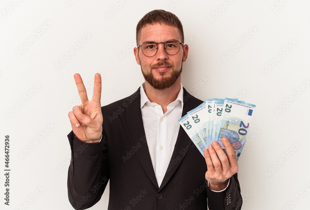 Young business caucasian man holding banknotes isolated on white background showing number two with fingers. Young business caucasian man holding banknotes isolated on white background showing number two with fingers.