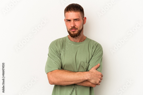 Young caucasian man with diastema isolated on white background frowning face in displeasure, keeps arms folded. © Asier