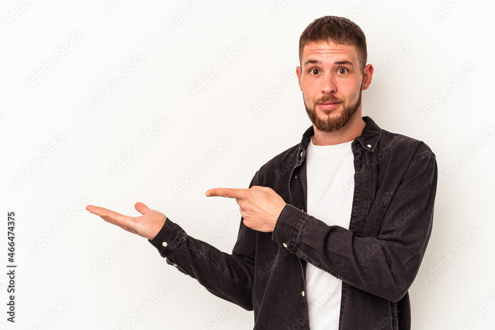 Young caucasian man with diastema isolated on white background excited holding a copy space on palm. Young caucasian man with diastema isolated on white background excited holding a copy space on palm.